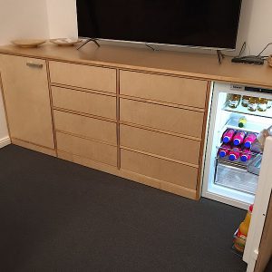 Ein Schrank aus Holz mit Schubladen und integriertem Kühlschrank